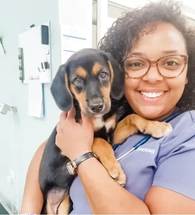 Vanessa Soto smiling holding a black and brown puppy Vanessa Soto smiling holding a black and brown puppy