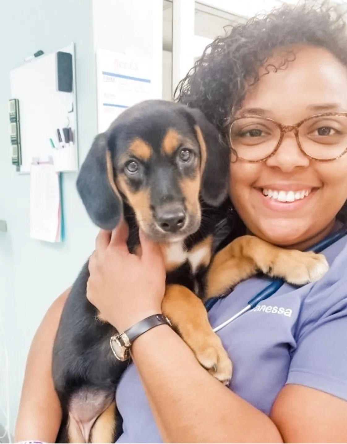 Vanessa Soto smiling holding a black and brown puppy Vanessa Soto smiling holding a black and brown puppy