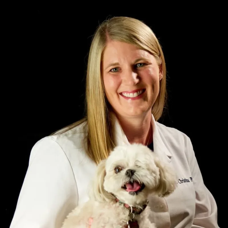 Dr. Christina Phillip holding a small white dog Dr. Christina Phillip holding a small white dog