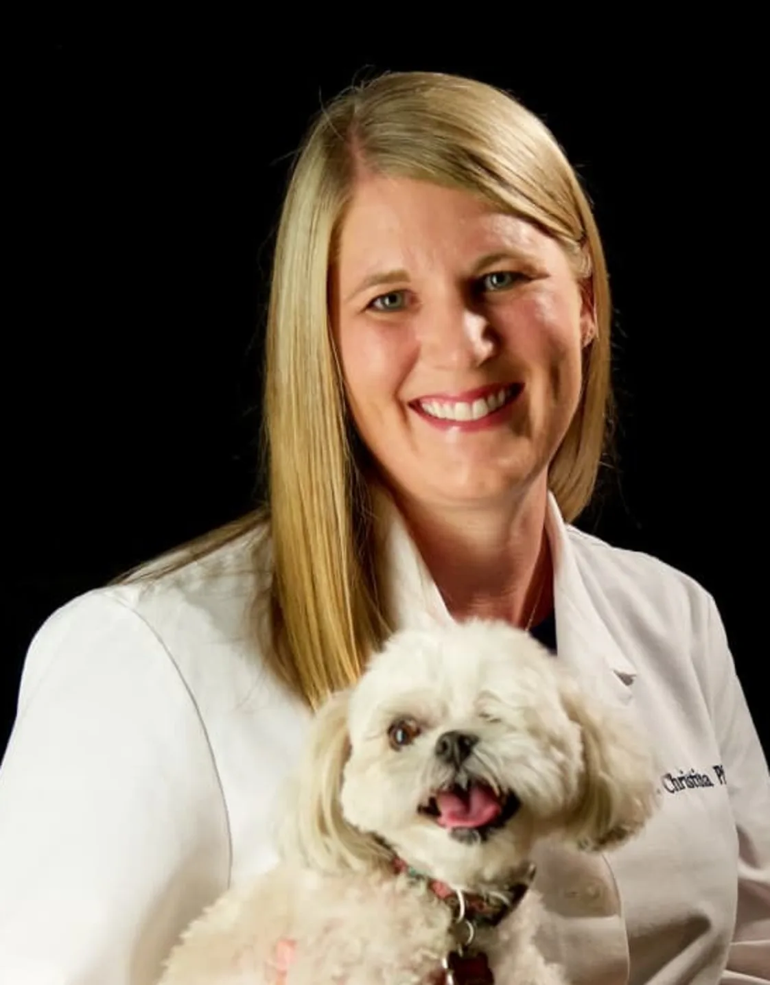 Dr. Christina Phillip holding a small white dog Dr. Christina Phillip holding a small white dog