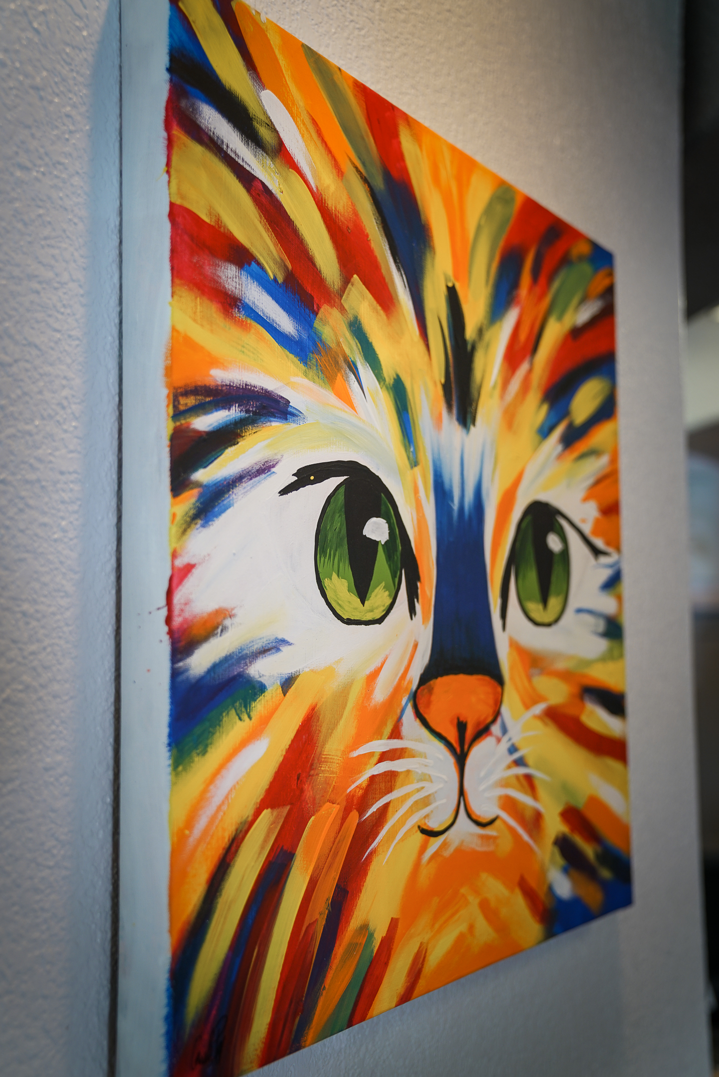 a colorful painting of a cat's face on the wall of the Great Oaks Animal Hospital lobby