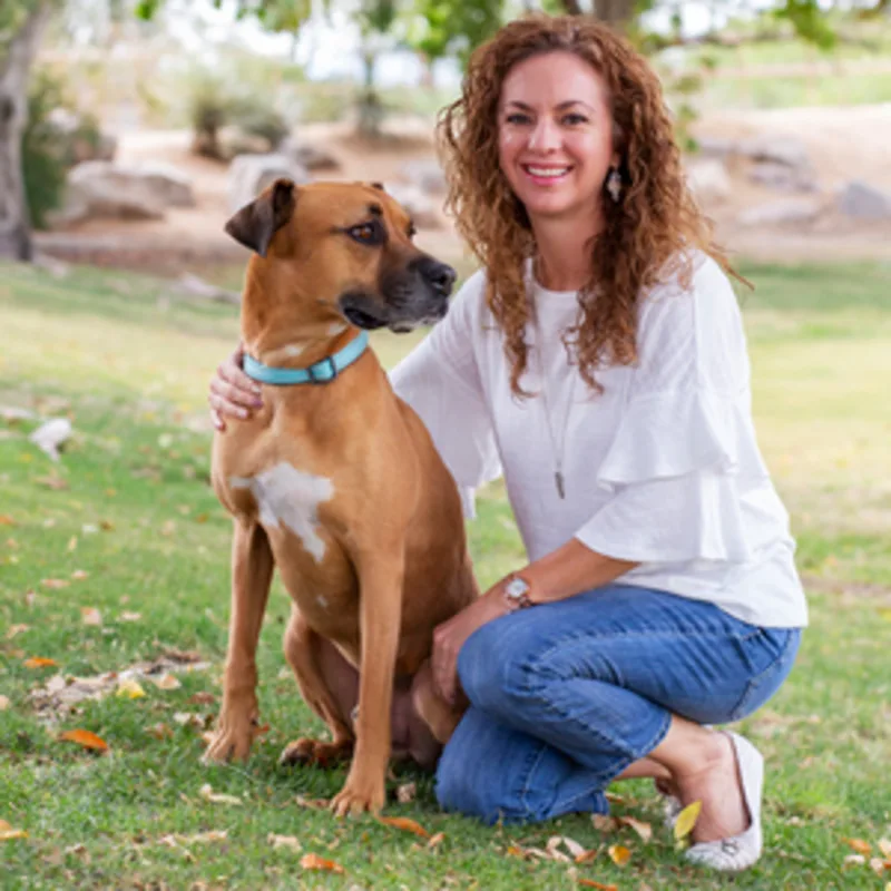 Brittney Carpenter kneeling next to a tan dog with a blue collar Brittney Carpenter kneeling next to a tan dog with a blue collar