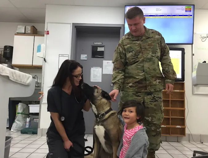 Staff with patient and owners in clinic Staff with patient and owners in clinic