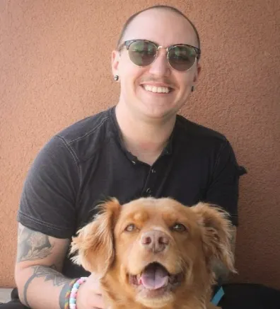 Ryan crouching down and posing with a happy looking, long-haired dog
