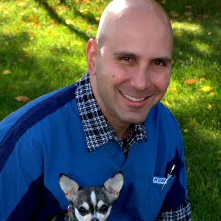 Dr. Gerald Gyorffy sitting in grass holding a small dog