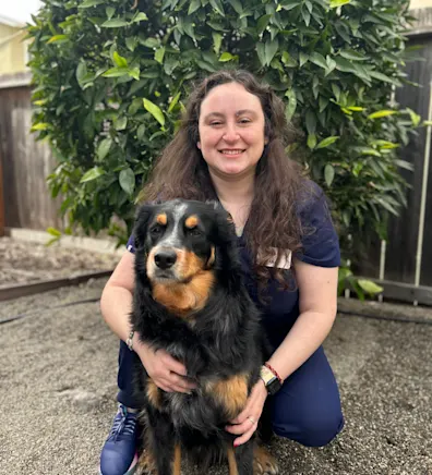 A staff member posing with black dog A staff member posing with black dog