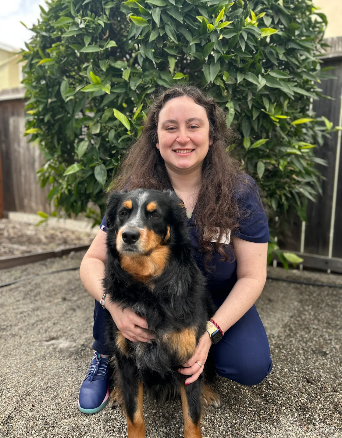A staff member posing with black dog A staff member posing with black dog