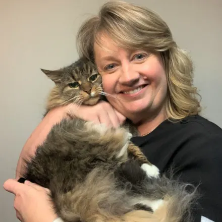 Dr. Elizabeth Patrick, DVM smiling and holding a long haired cat close to her face