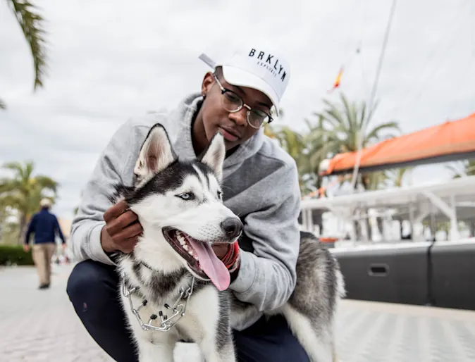 man petting husky on the board walk