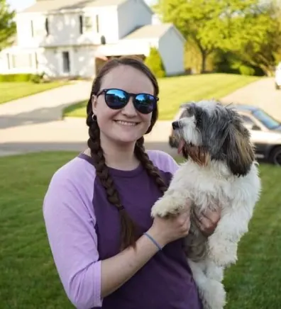 Alyssa, veterinary technician, holding dog wearing sunglasses