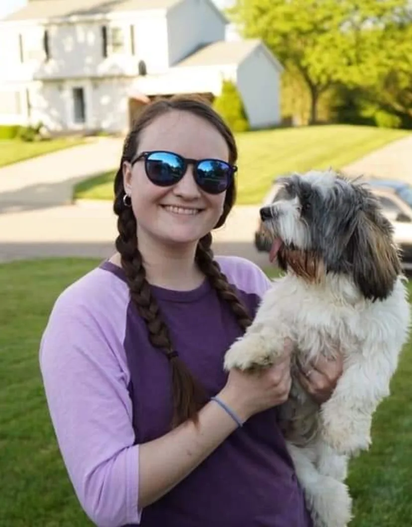 Alyssa, veterinary technician, holding dog wearing sunglasses