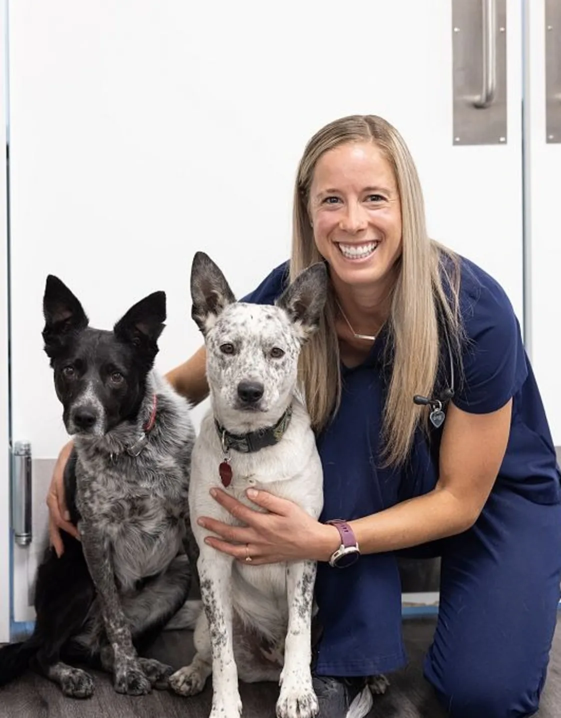 Dr. Katie Bennett smiling while holding onto two dogs. Dr. Katie Bennett smiling while holding onto two dogs.