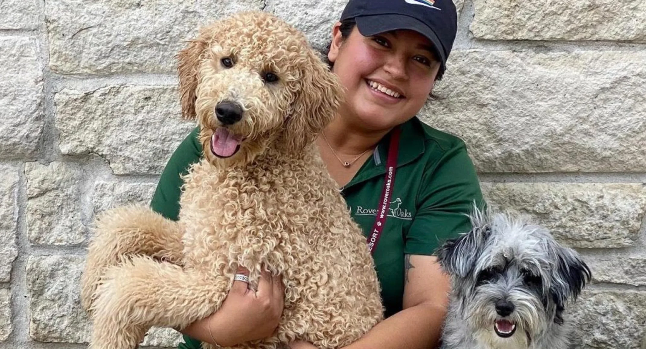 A woman holds a dog while another dog is next to her smiling in the photo