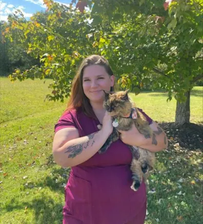 Jessica holding a calico cat while smiling in front of a tree in a sunny day. Jessica holding a calico cat while smiling in front of a tree in a sunny day.