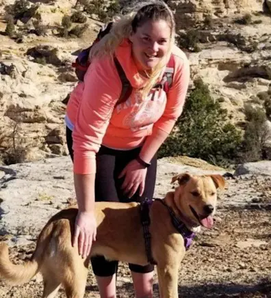 Ashley petting a dog in a desert