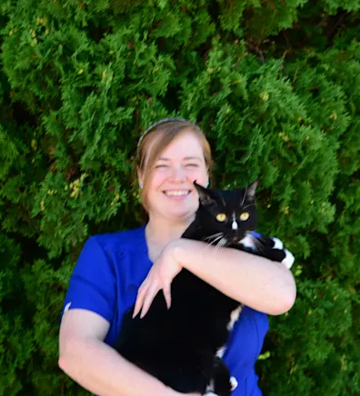 Kira hugging a cat in front of the Eastside sign