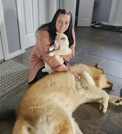 Leona Compton holding onto a cat and petting a dog. Leona Compton holding onto a cat and petting a dog.
