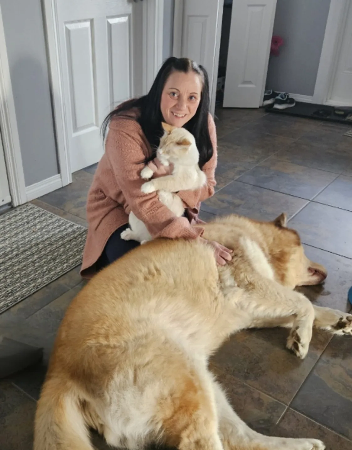 Leona Compton holding onto a cat and petting a dog. Leona Compton holding onto a cat and petting a dog.