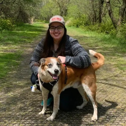 Dr. Katarzyna Gibas' staff photo from Elmwood Grove Animal Hospital where she is sitting next to her dog on a hiking trail.