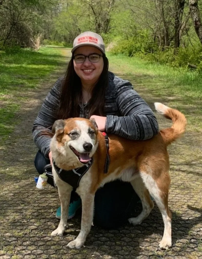 Dr. Katarzyna Gibas' staff photo from Elmwood Grove Animal Hospital where she is sitting next to her dog on a hiking trail.