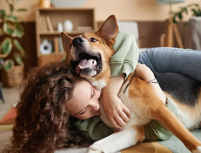 Woman laying on the floor with her arms wrapped around and cuddling a dog. Woman laying on the floor with her arms wrapped around and cuddling a dog.