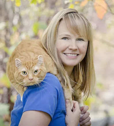 Kristina holding an orange cat on her shoulders