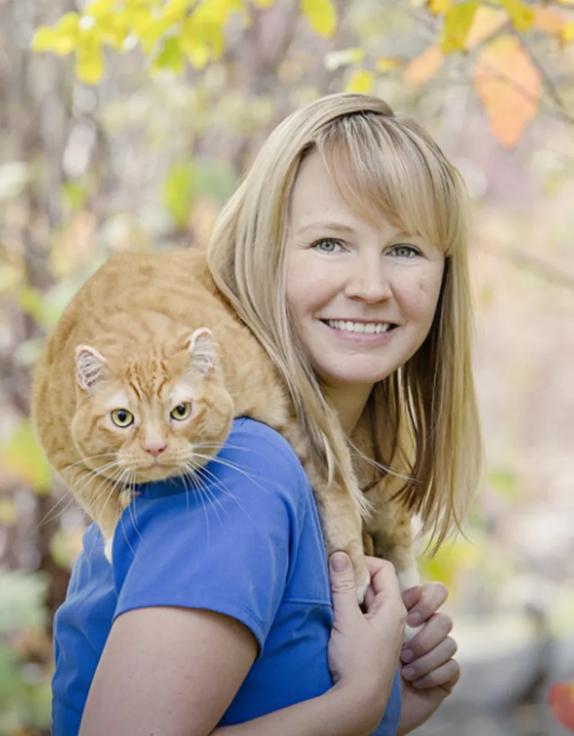 Kristina holding an orange cat on her shoulders