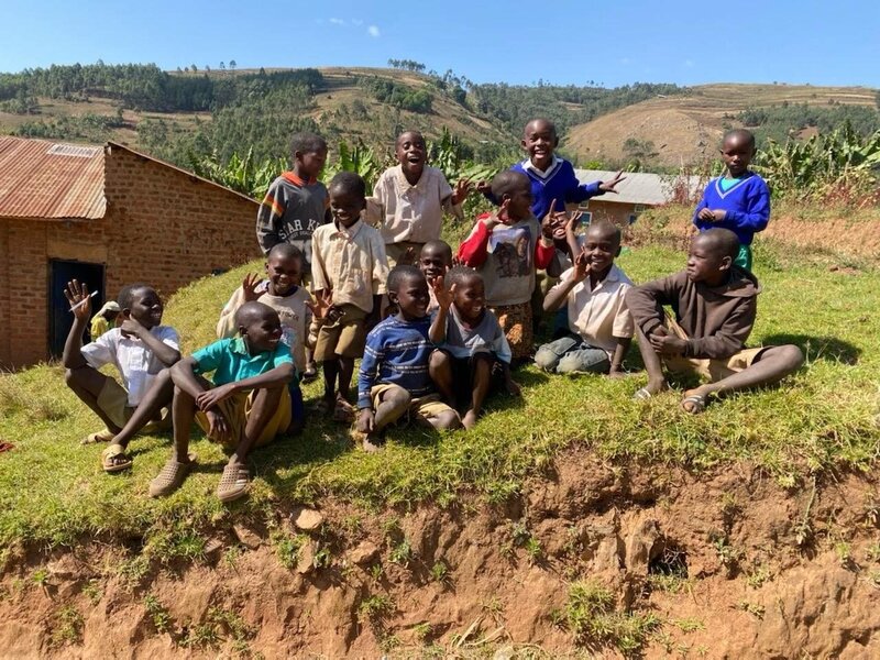 A group of kids smiling sitting on a hill side
