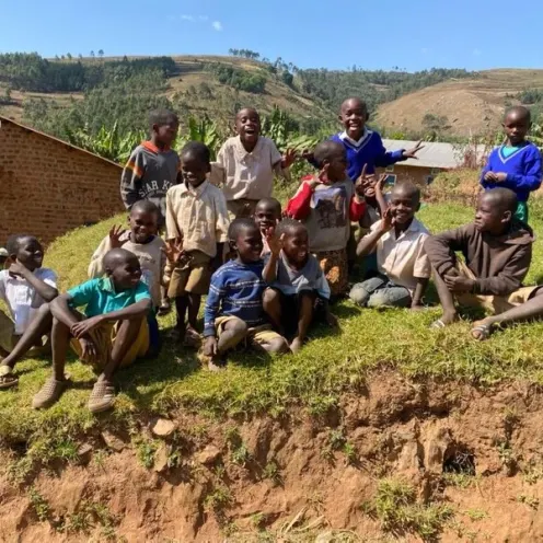 A group of kids smiling sitting on a hill side