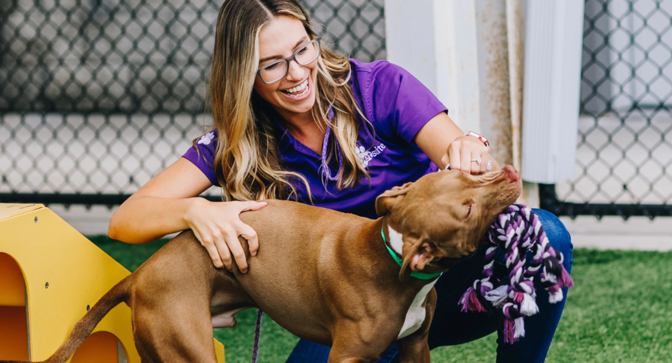 A PetSuites staff member plays with a dog. A PetSuites staff member plays with a dog.