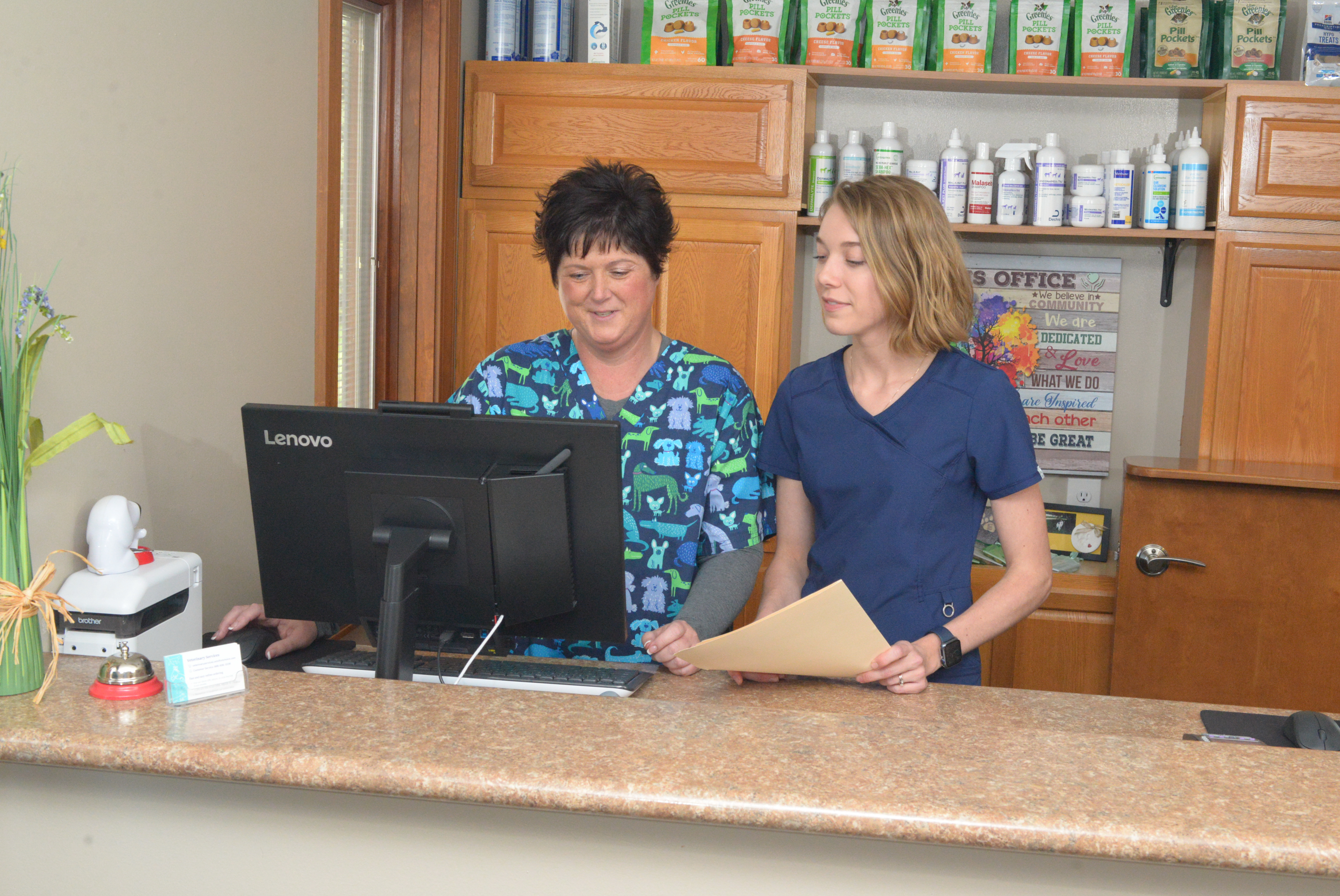 Two veterinary staff at the front desk looking at a computer screen