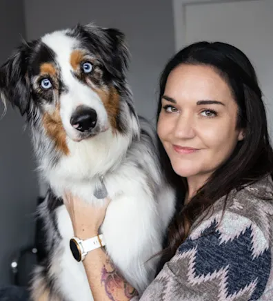 Lauren holding a black, white, and tan dog with blue eyes Lauren holding a black, white, and tan dog with blue eyes