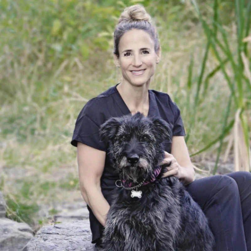 Dr. Jennifer Watt sitting with a black dog outside Dr. Jennifer Watt sitting with a black dog outside