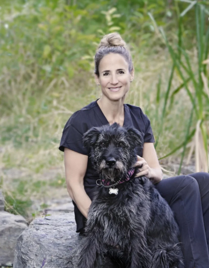 Dr. Jennifer Watt sitting with a black dog outside