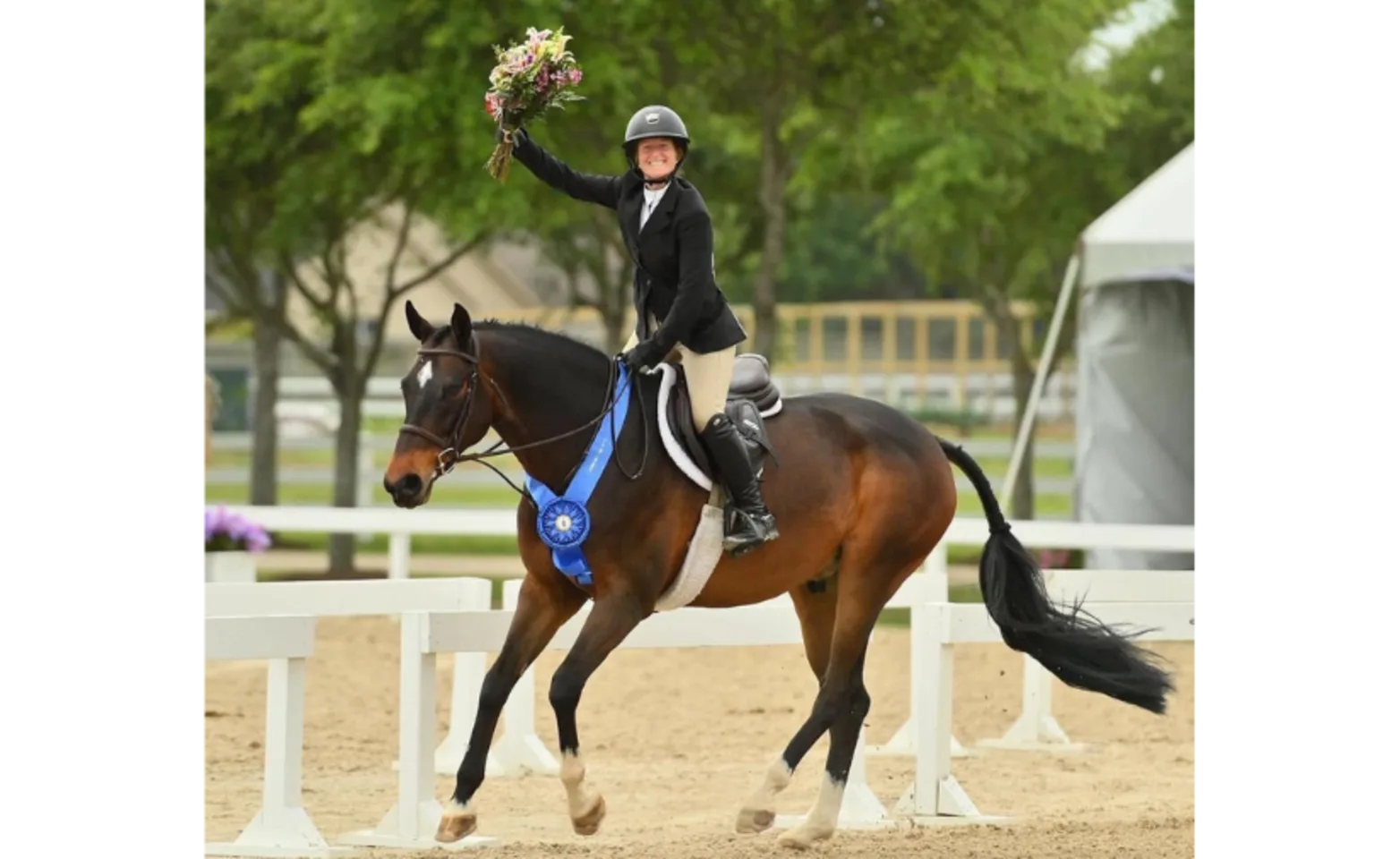 A horse wearing ribbon and their rider holding flowers