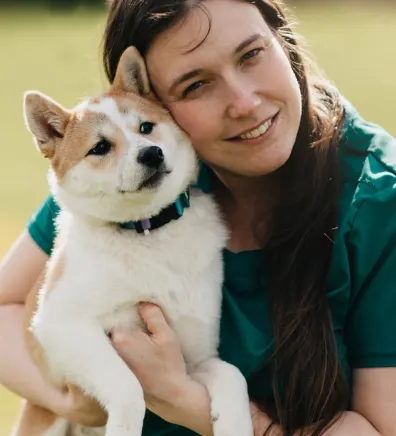 Dr. Danielle Kepler holding a tan and white Shiba Inu dog