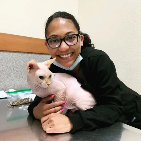 Woman in black glasses hugging hairless cat.