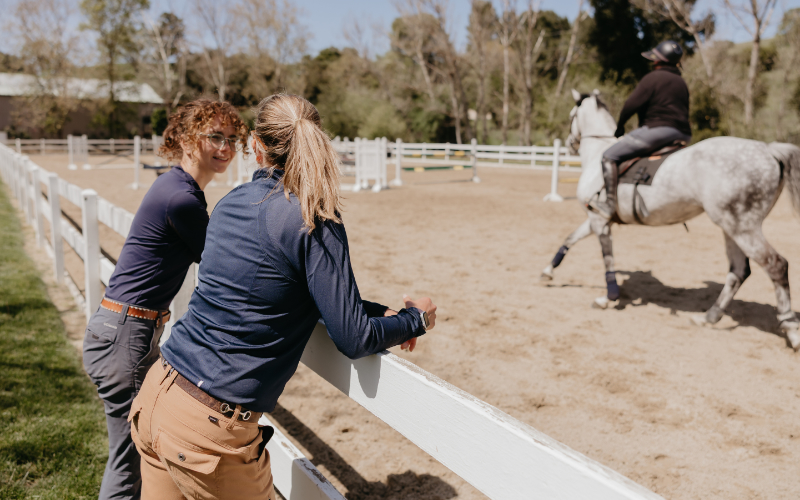 Two Staff Members Leaning Against Fence Talking