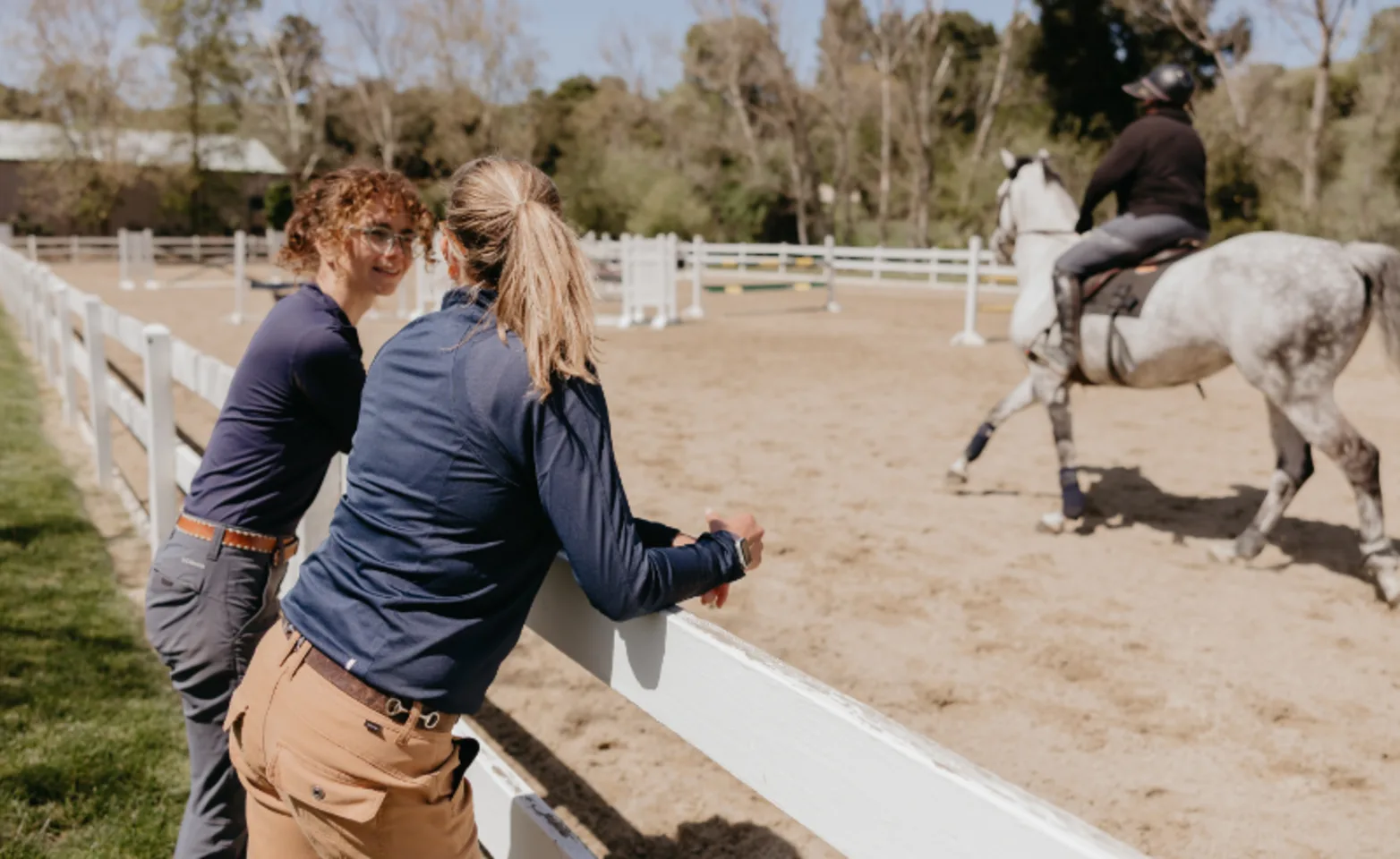 Two Staff Members Leaning Against Fence Talking Two Staff Members Leaning Against Fence Talking