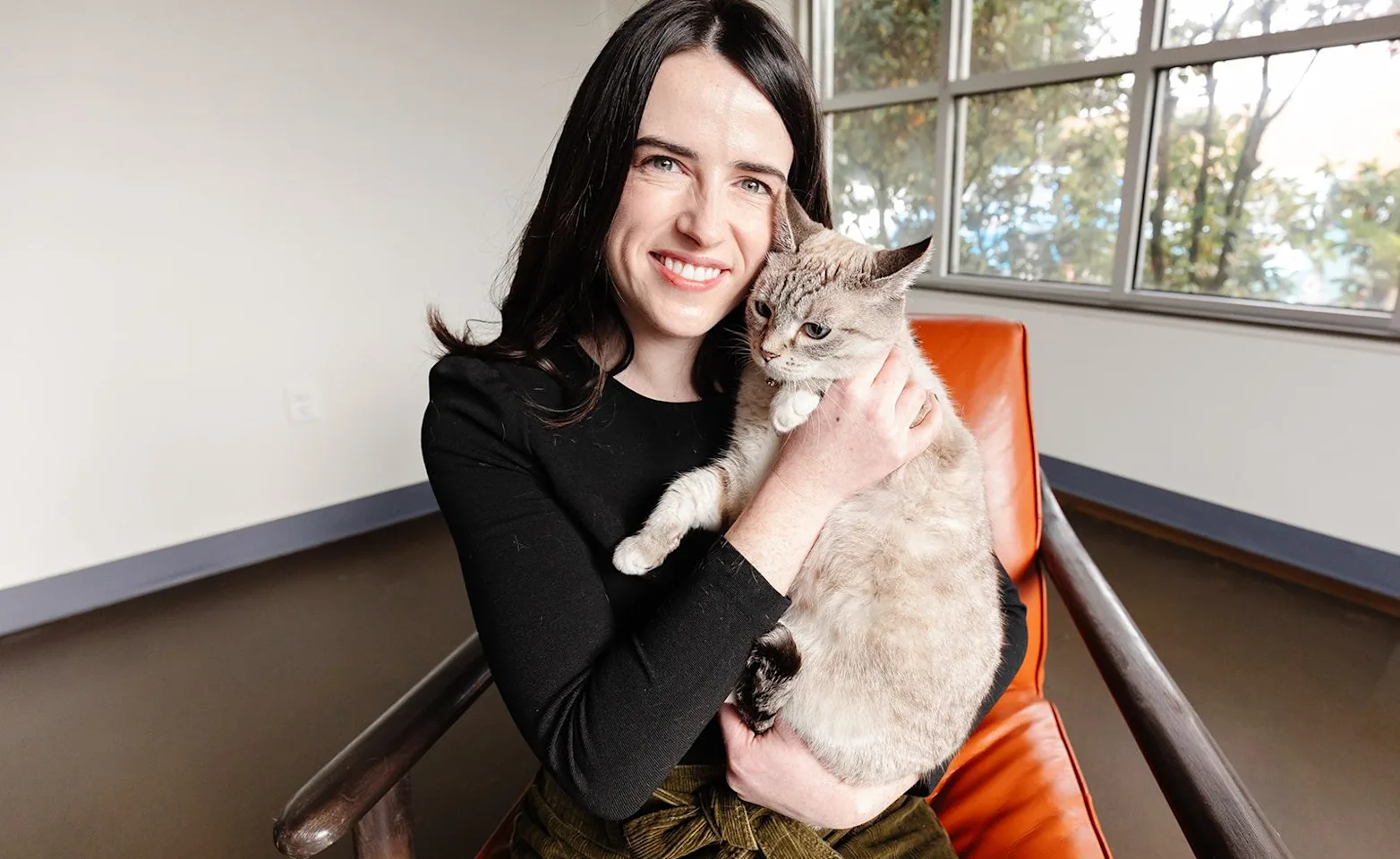 Smiling woman sitting in a chair holding a cat Smiling woman sitting in a chair holding a cat