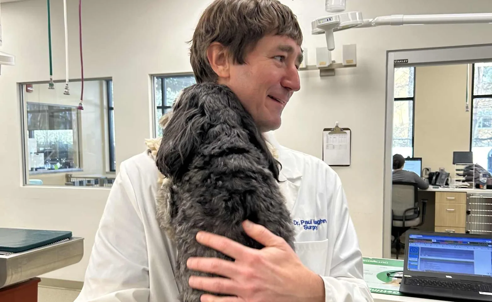 Dr. Vaughn hugging gray dog. Dr. Vaughn hugging gray dog.