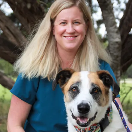 Dr. Jennifer Bucher smiling next to large dog
