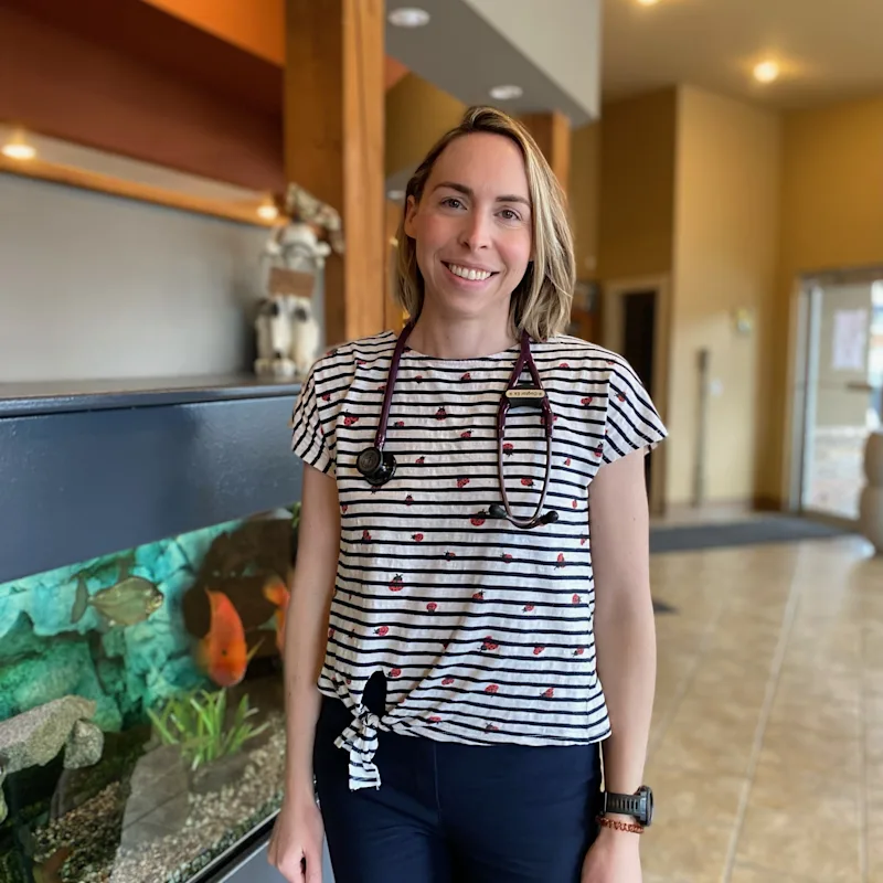 Dr. Courtney Ek smiling standing next to an aquarium Dr. Courtney Ek smiling standing next to an aquarium