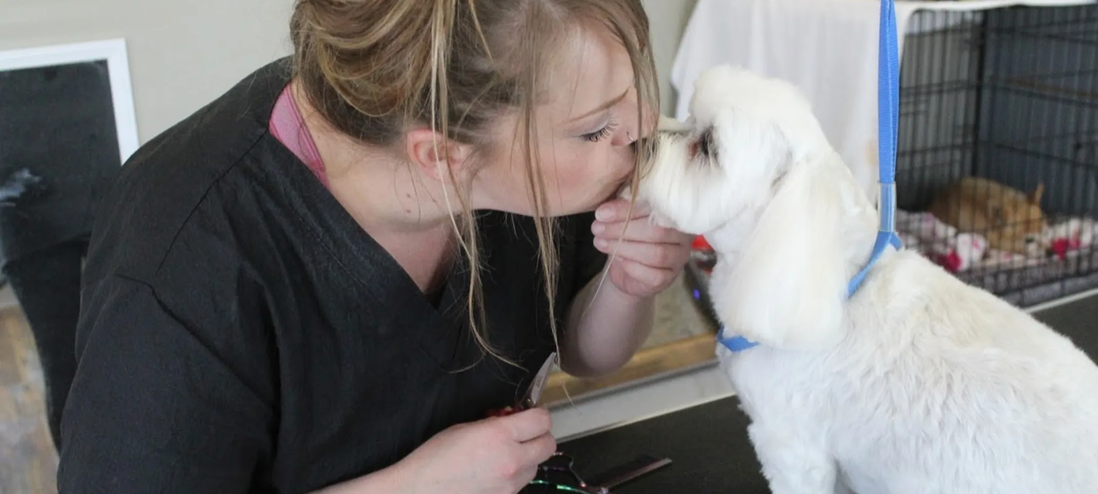 Groomer and dog sharing a nose kiss
