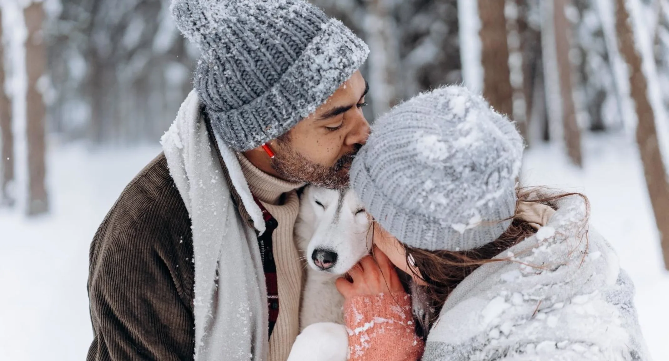 a man and woman embracing their dog outside in the snow a man and woman embracing their dog outside in the snow