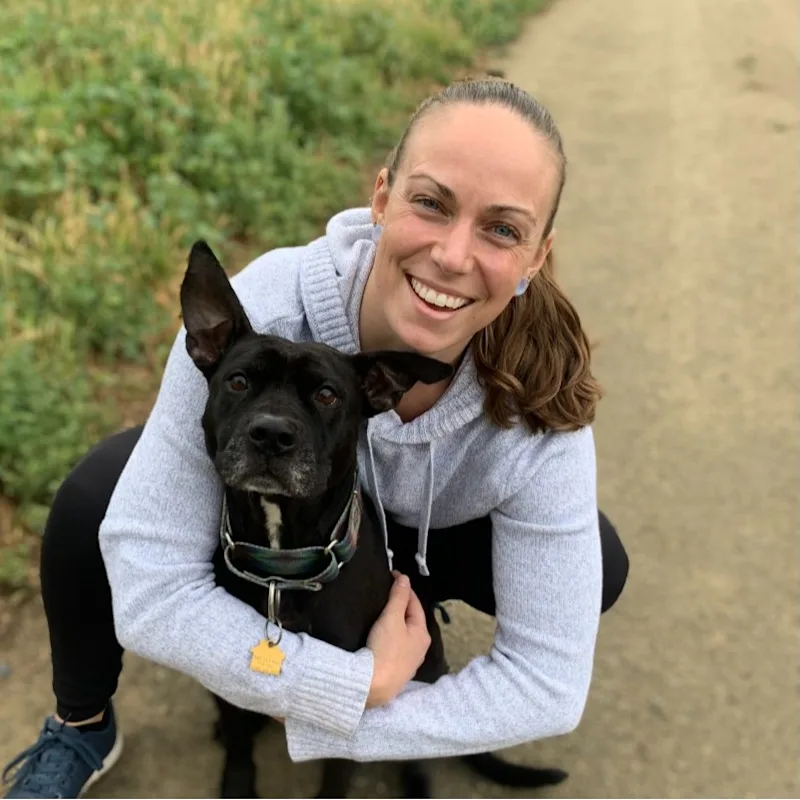 DVM Nicole smiling hugging a dog. DVM Nicole smiling hugging a dog.