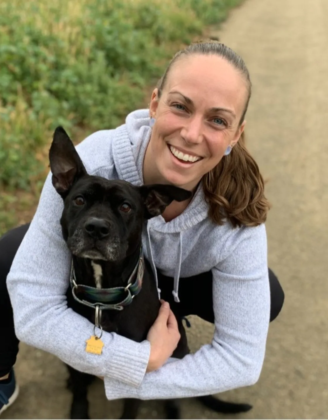 DVM Nicole smiling hugging a dog. DVM Nicole smiling hugging a dog.