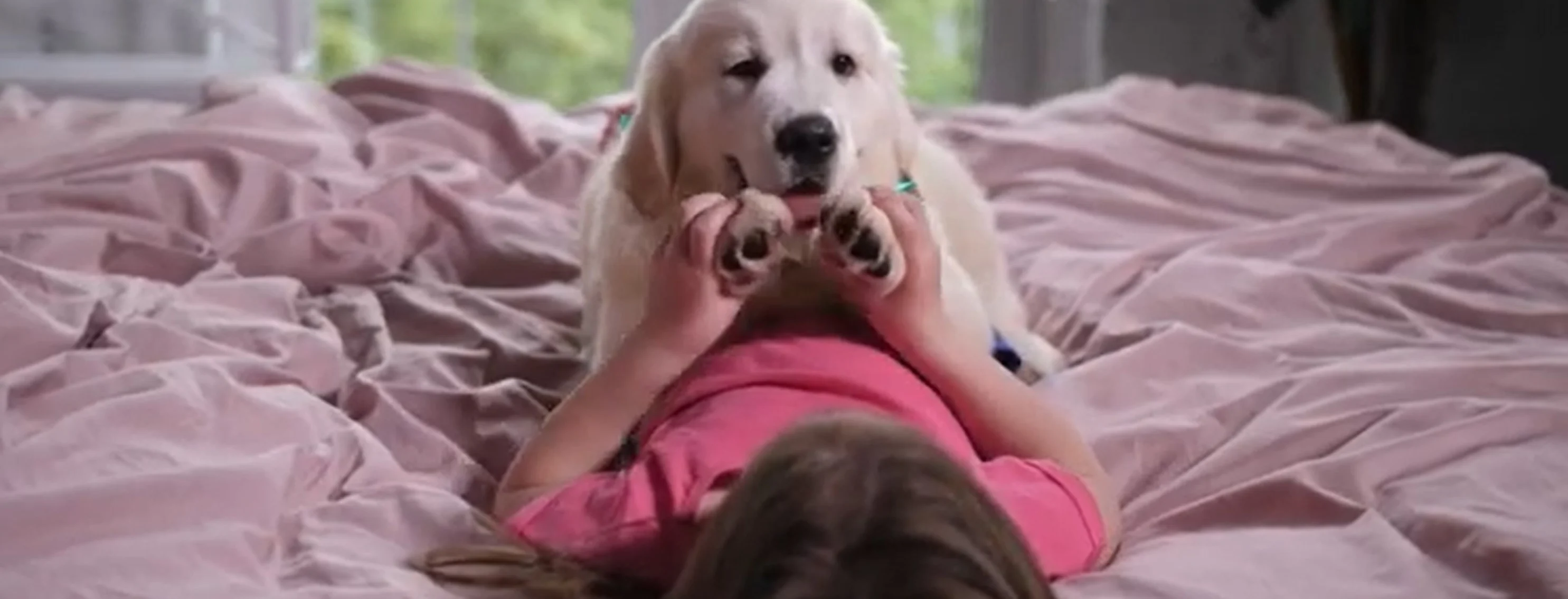 Girl and puppy laying on bed