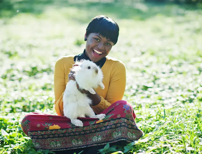 Woman sitting in grass holding a rabbit