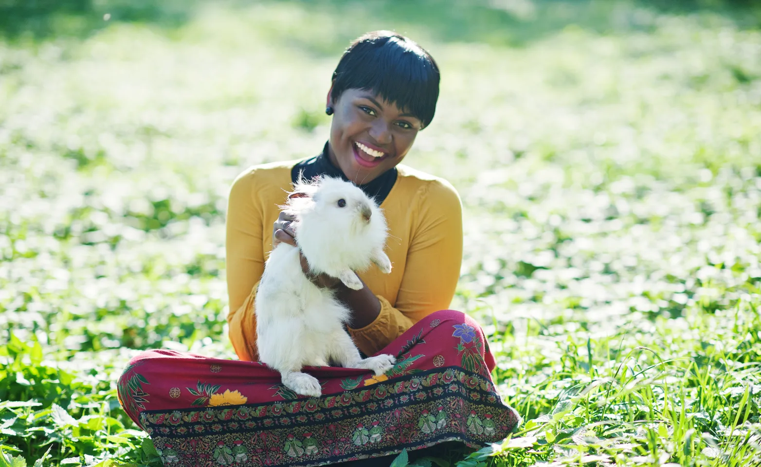 Woman sitting in grass holding a rabbit